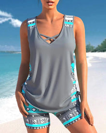 Two-piece tankini in gray with a sleeveless top featuring cross straps and patterned shorts in turquoise and black.
