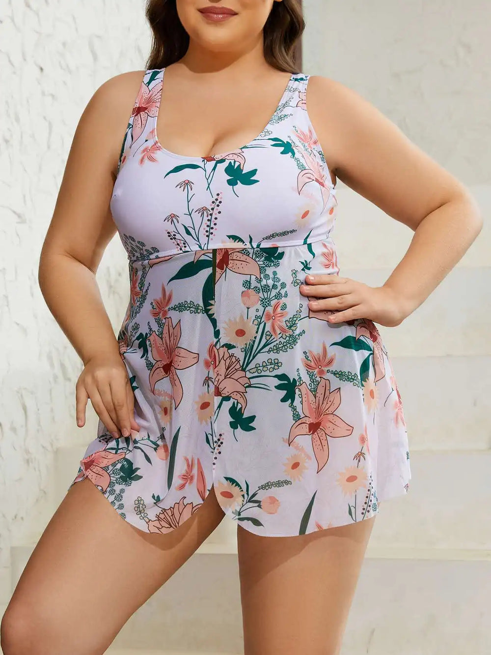 Floral skirted swim dress with a round neckline, broad straps, and a flowing skirt in pink and green hues.