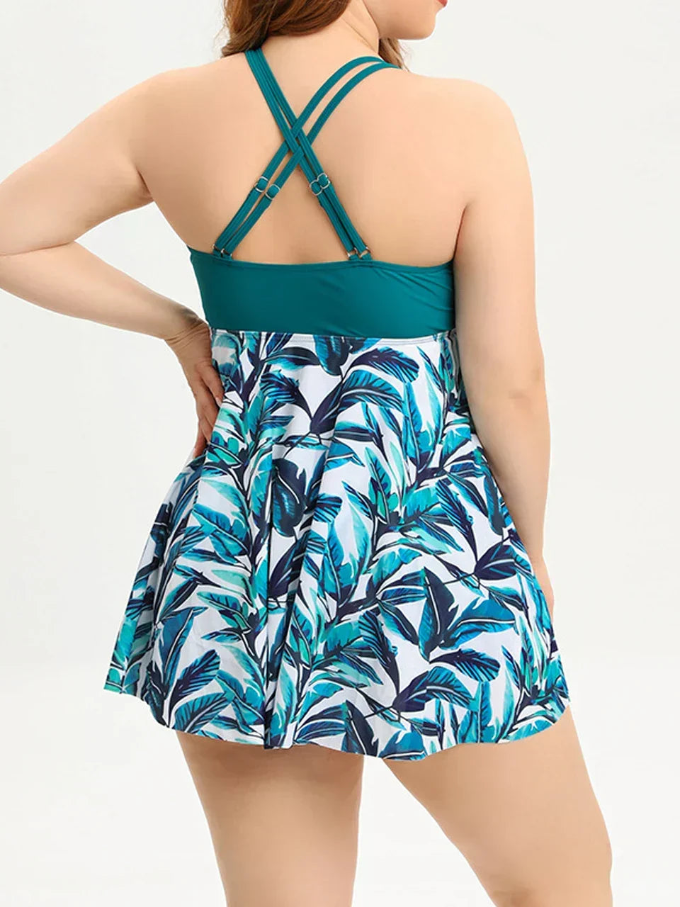 Asymmetrical overlay tankini set in teal and white with tropical leaf print; features crossback wide straps and flowing design.