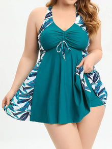 Asymmetrical overlay tankini set in teal with tropical print accents, featuring a V-neckline and wide straps.