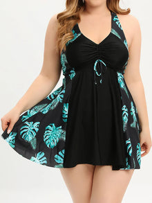 Asymmetrical overlay tankini set with a V-neckline, featuring a tropical print and flowing top in black and teal.