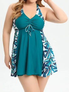 Teal asymmetrical tankini top with tropical leaf print side panels, V-neckline, and wide straps, styled for comfort.