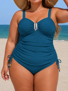 Teal adjustable-side tankini set with sweetheart neckline, supportive straps and side ruching, styled against a beach background.