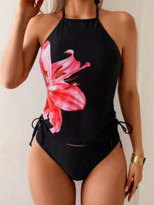 Black tankini set featuring a pink floral print, adjustable side ties, and a squared neckline, styled for summer wear.