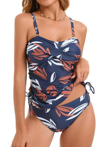 Tankini set featuring a navy background with tropical leaf patterns in white and coral, adjustable side ties, and spaghetti straps.