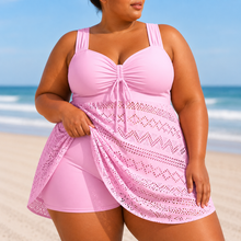 Flowing pink swim dress with a structured top, wide straps, and delicate overlay, styled for beachwear.