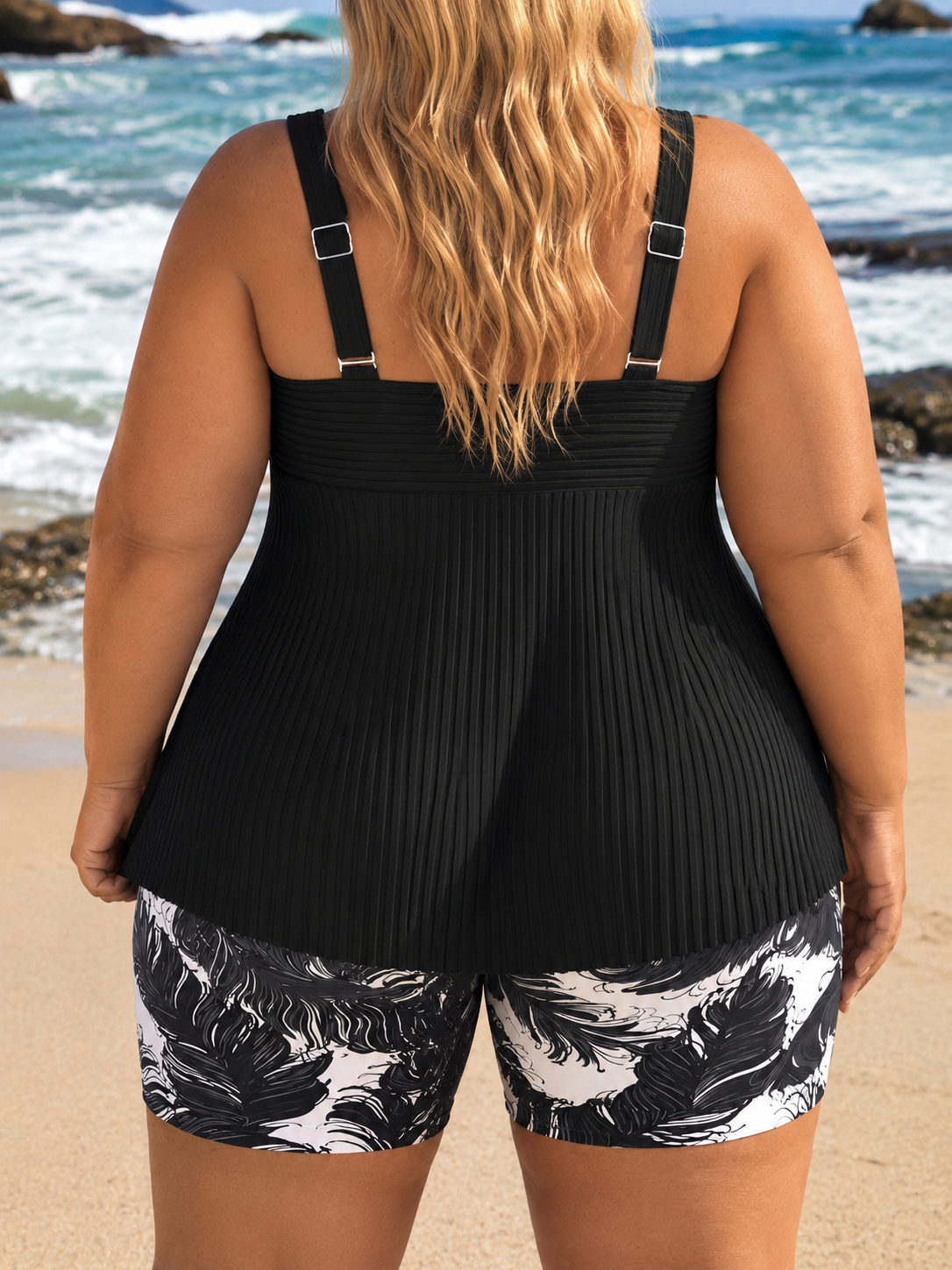 Black pleated tankini top with wide straps, paired with matching black-and-white feather print shorts, suitable for beach activities.
