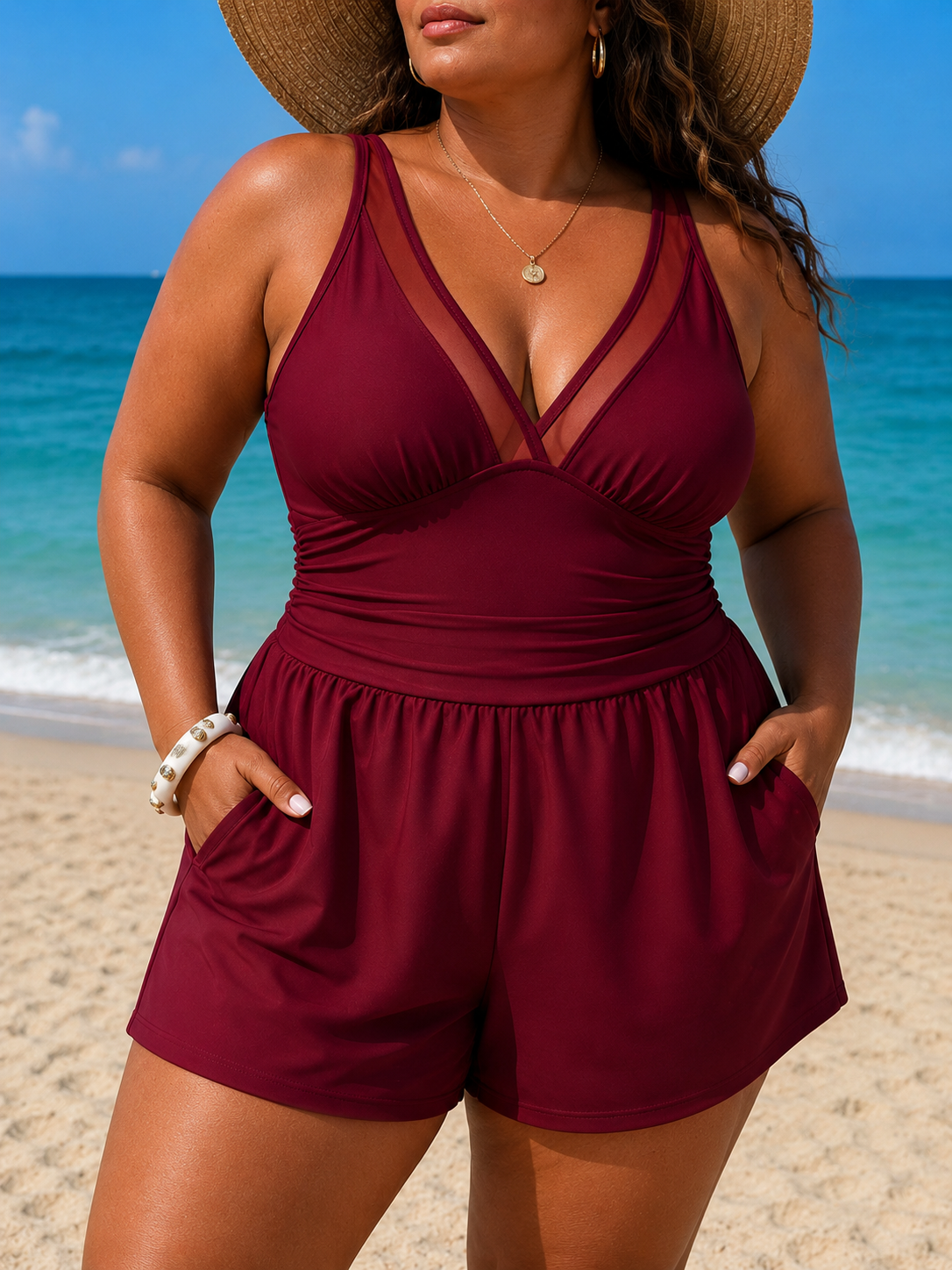 Maroon swim dress with a V-neck and wide straps, featuring a skirted design and built-in shorts, worn by a model at the beach.