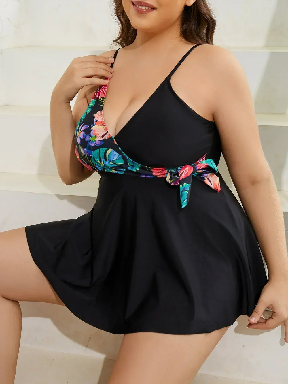 Tropical print swim dress with a V-neckline and adjustable straps. Black body with a colorful floral side tie.